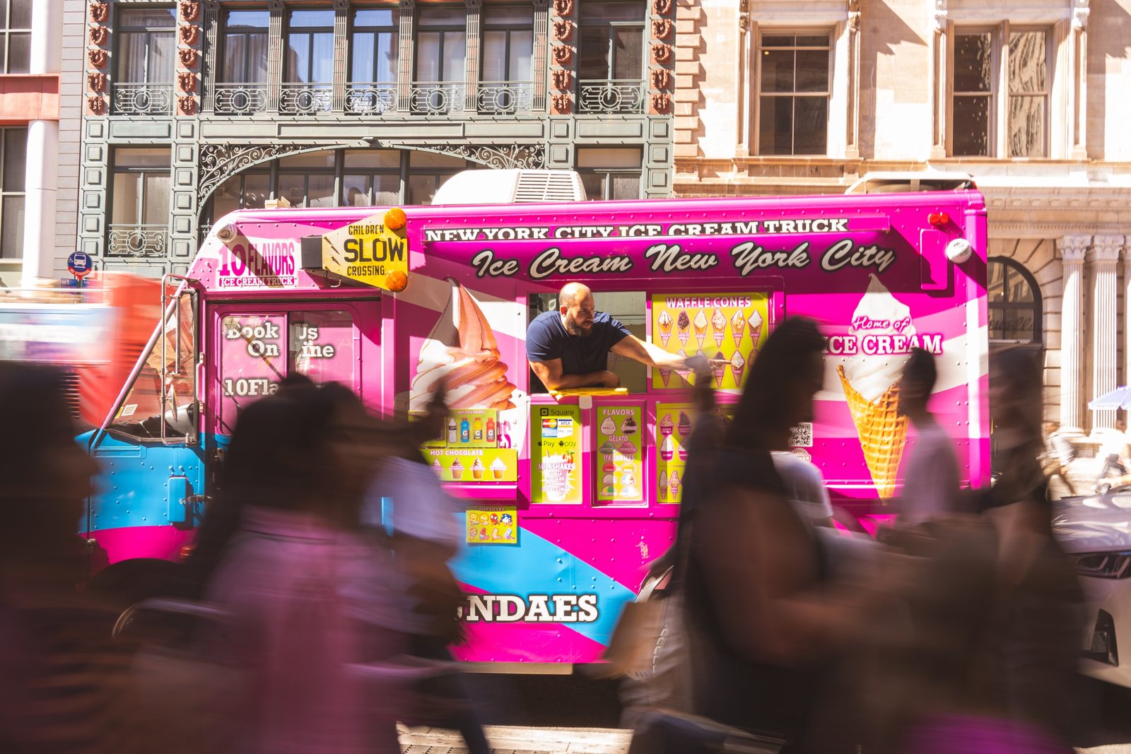 10 Flavors crew member serving an ice cream cone to a customer in a busy NYC crowd