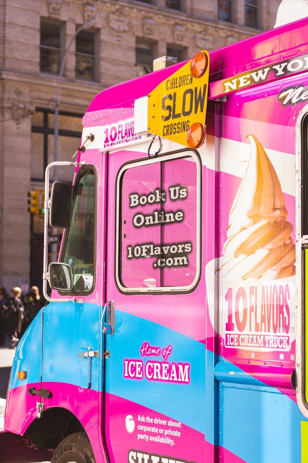 Close-up of the 10 Flavors ice cream truck cab with a Children Slow Crossing sign and Book Us Online window